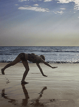 Picture of Jennifer Ann Crecente at the age of 15 doing a cartwheel on the beach in Mazatlan, Mexico;
            her image is reflected in the wet sand and blue skies are above.